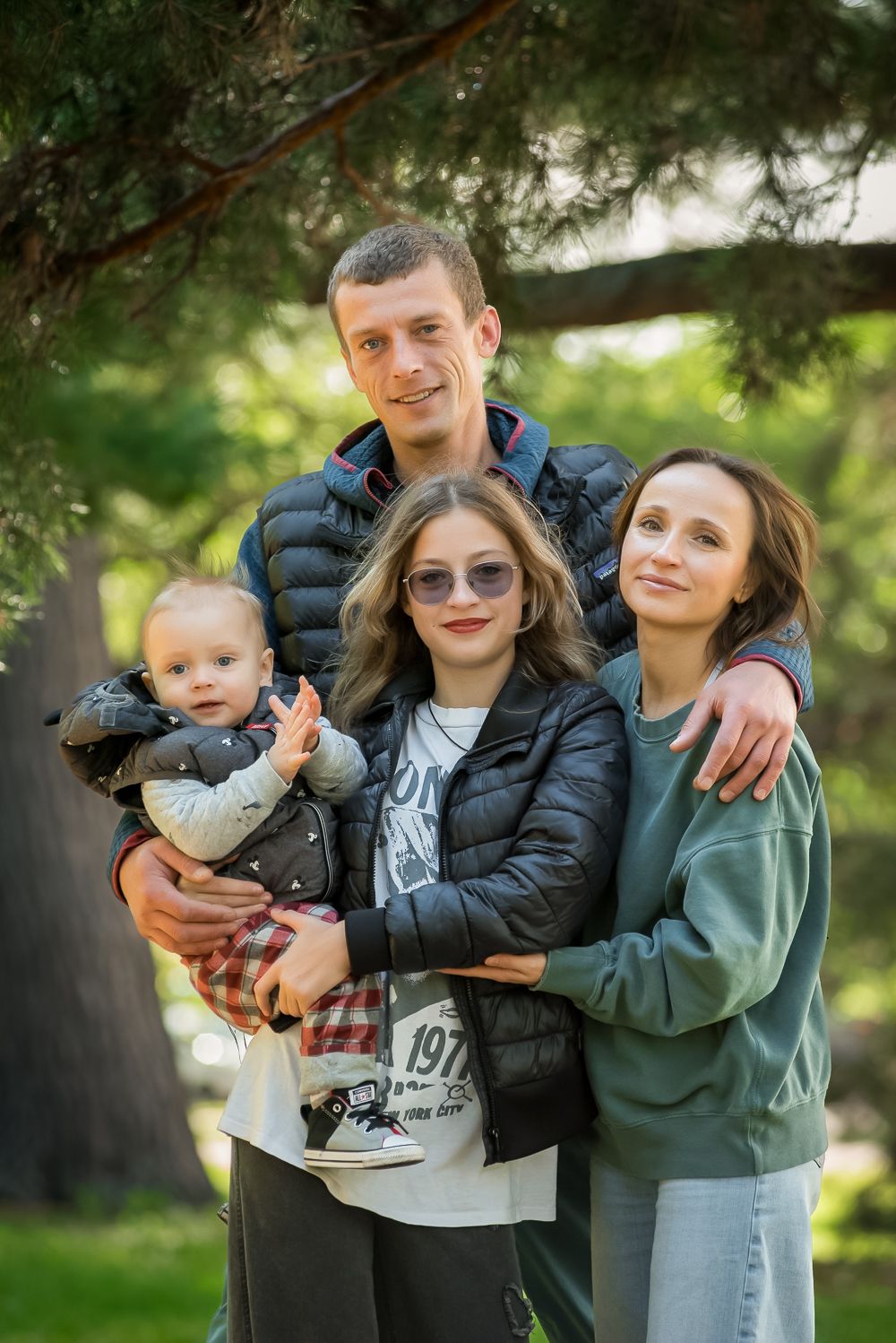 Casual family photo session outdoors with natural greenery background.