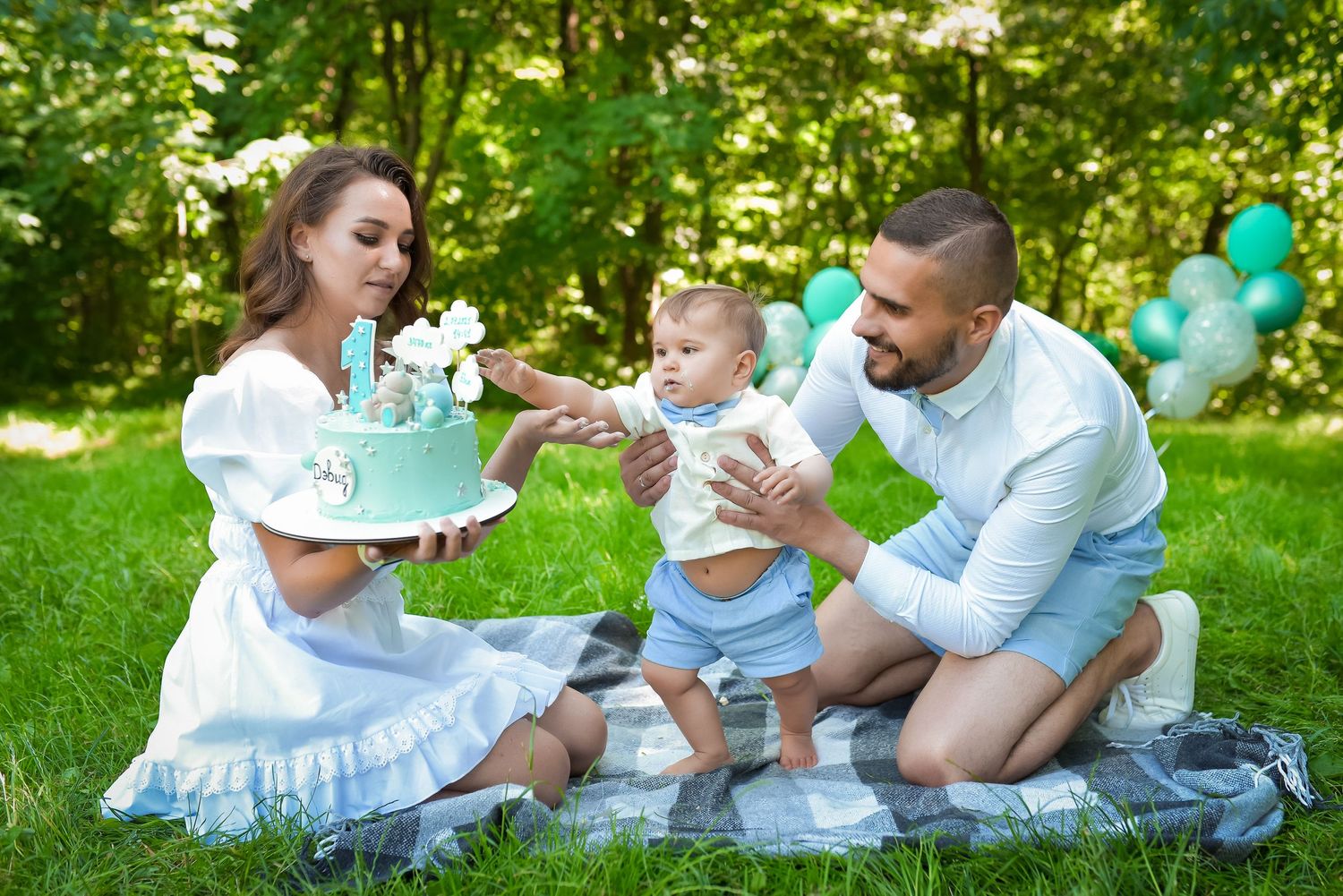 Family enjoying picnic on blanket in lush green park setting.