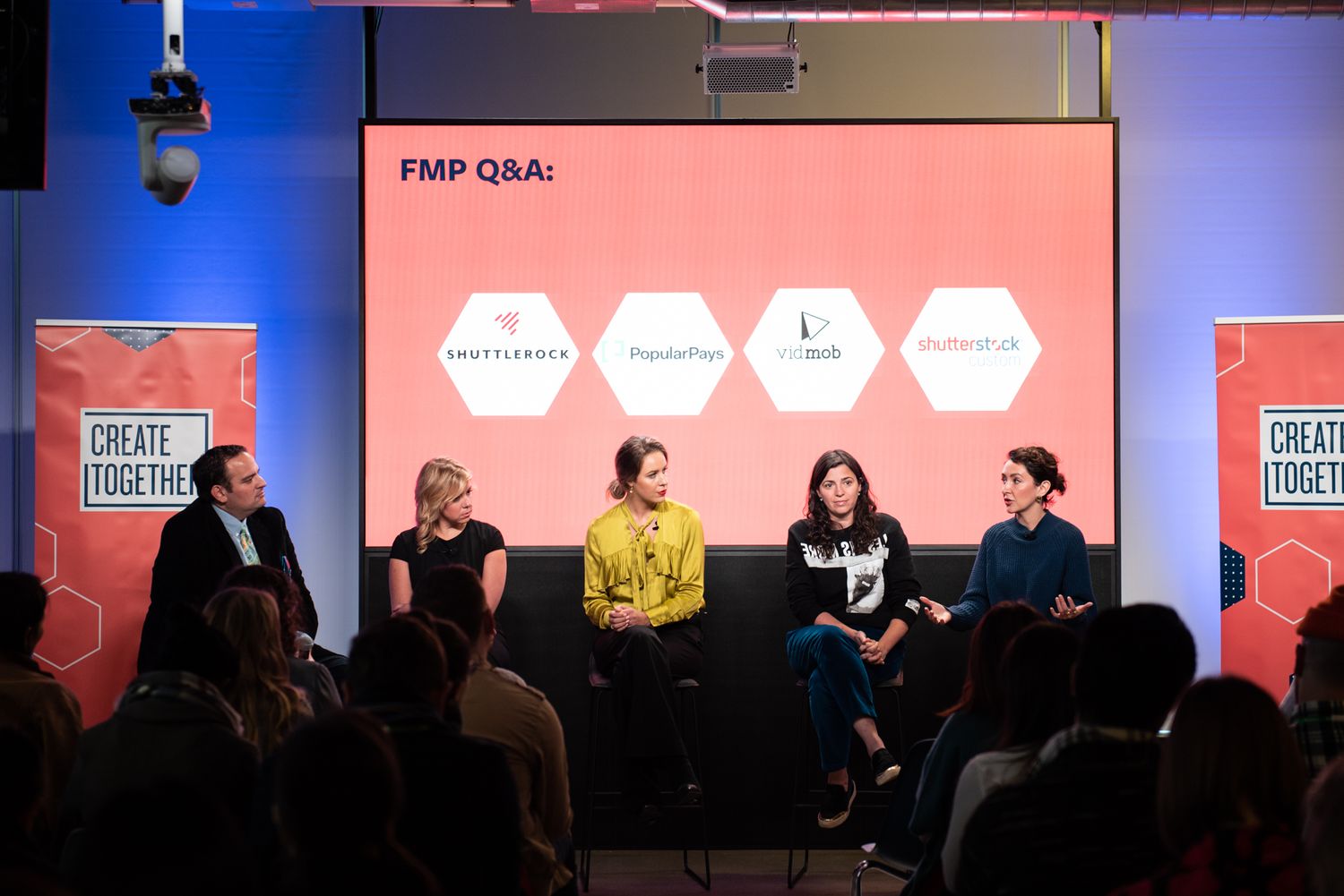 Panel discussion with speakers on stage at a business conference with red and blue lighting.