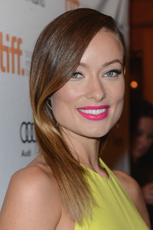 Woman wearing bright yellow dress smiles on red carpet at film festival.