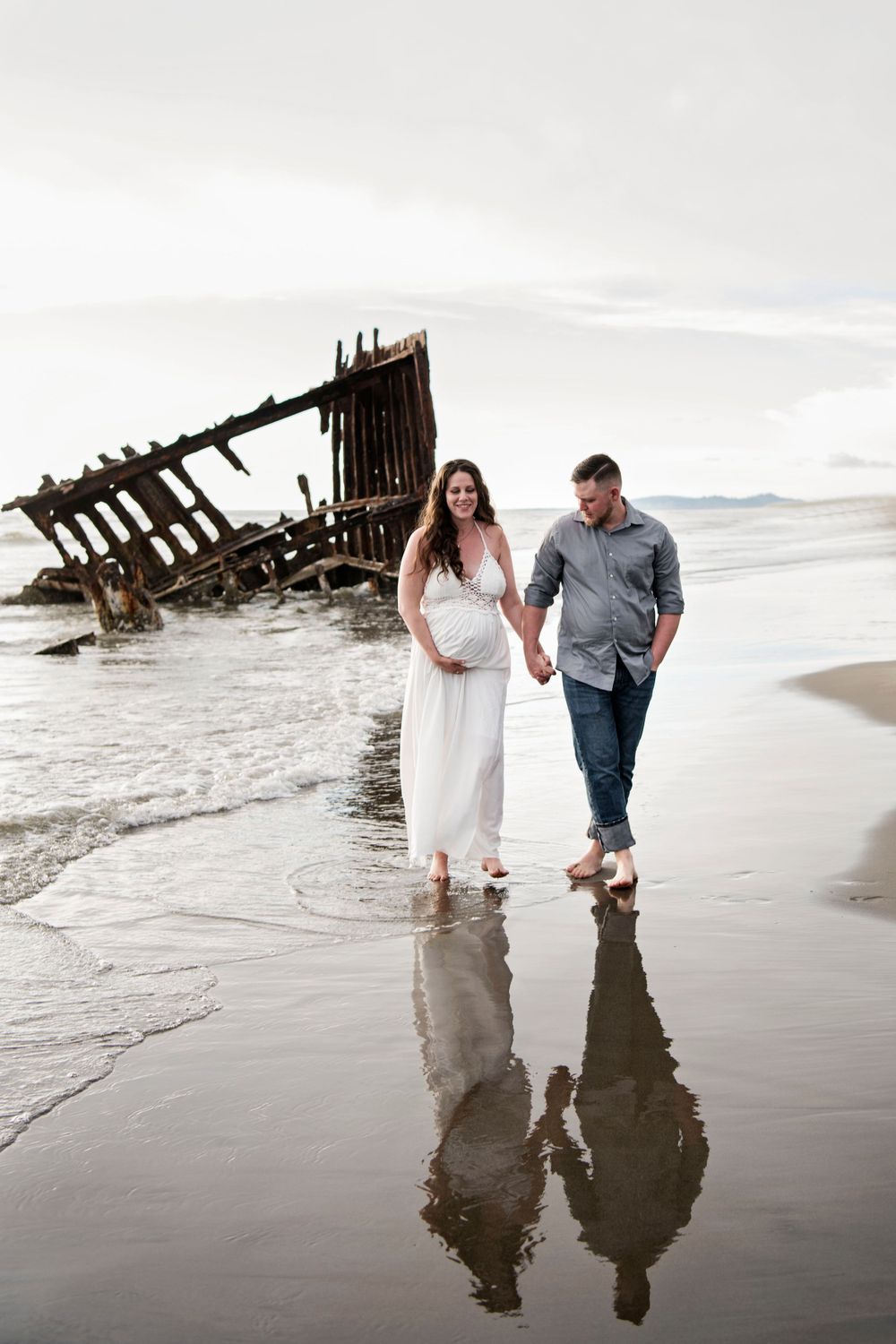 Husband walking with pregnant wife at Peter Iredale Beach