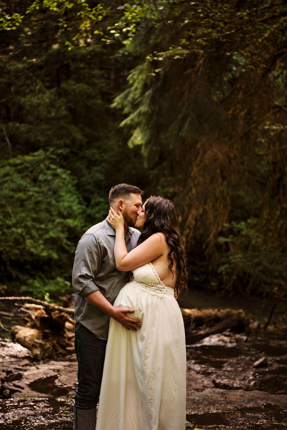 Pregnant wife kissing husband at Gnat Creek Falls