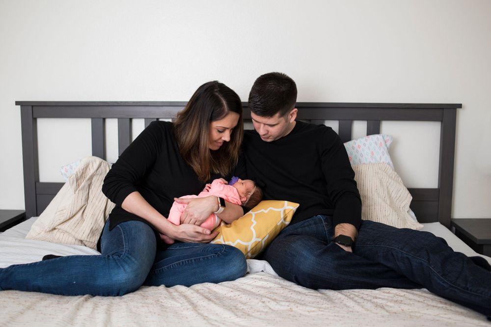 Young couple on bed holding a newborn