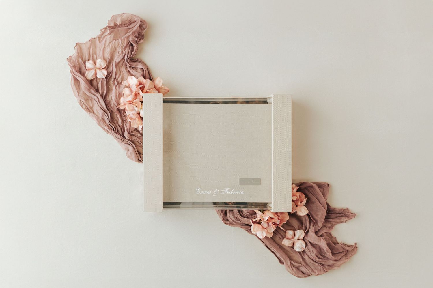 Elegant wedding photo album box with blush pink flowers and dusty rose fabric on white.