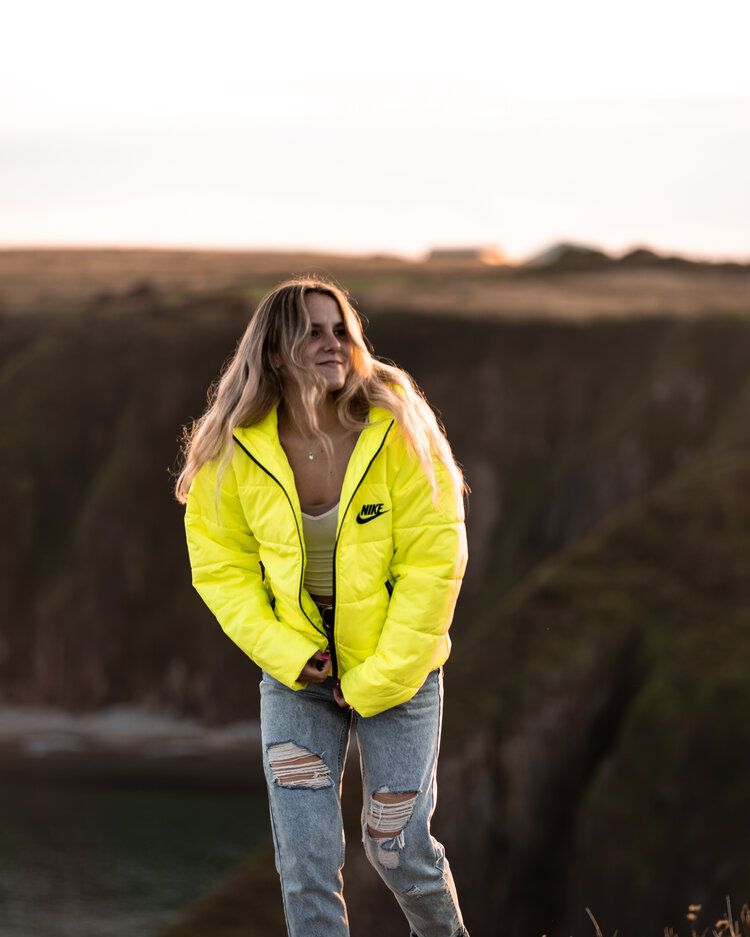 A bright neon yellow Nike puffer jacket styled with distressed jeans at sunset.