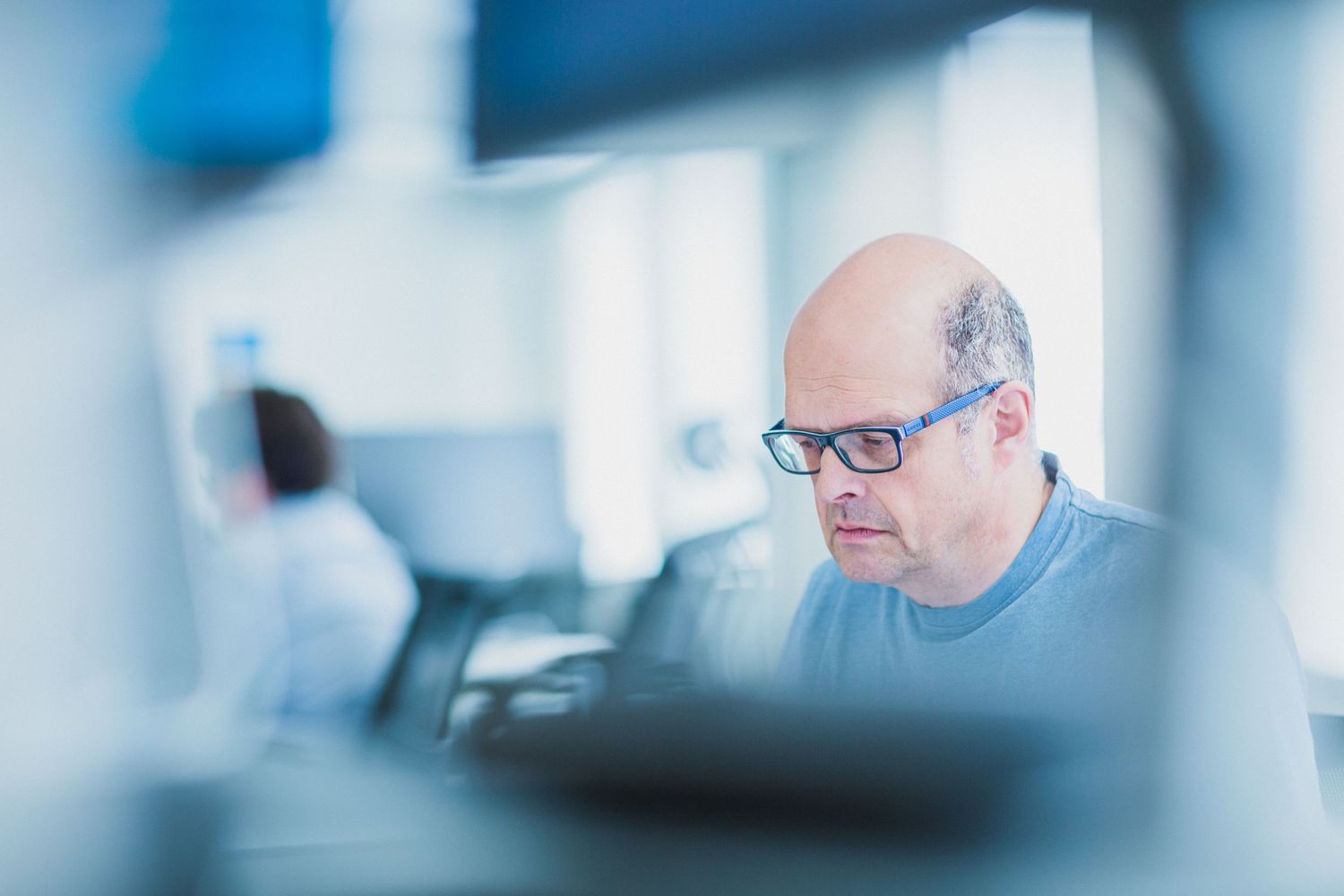 Person working at computer in modern office environment with blue toned lighting.