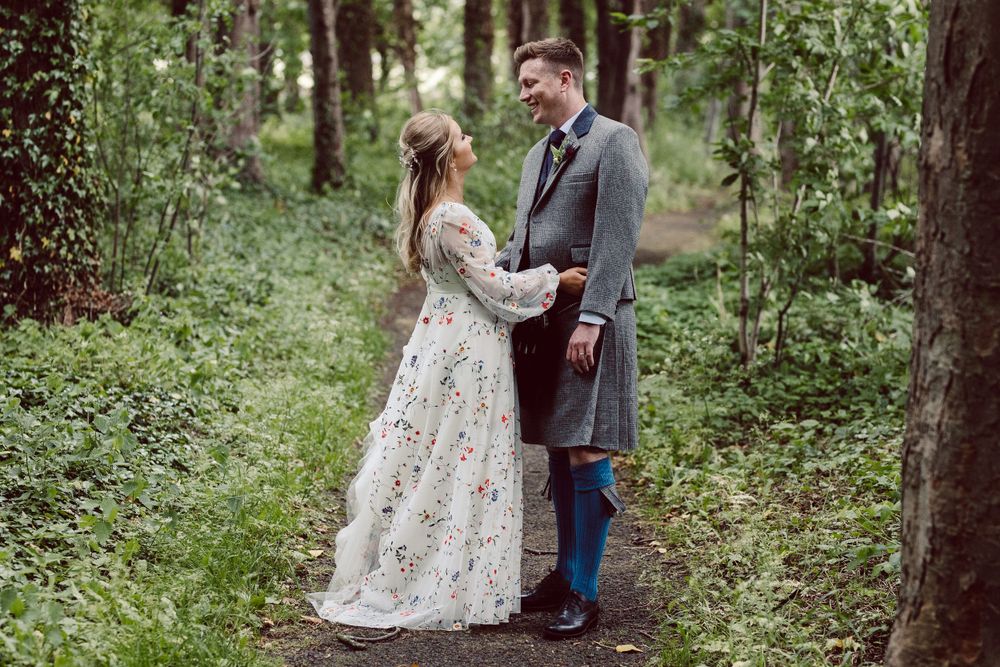 bride and groom embrace in the woods