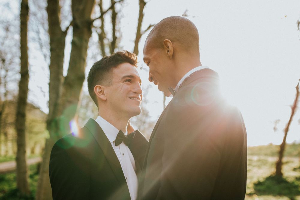 Two grooms look into each others eyes with golden light shining on them