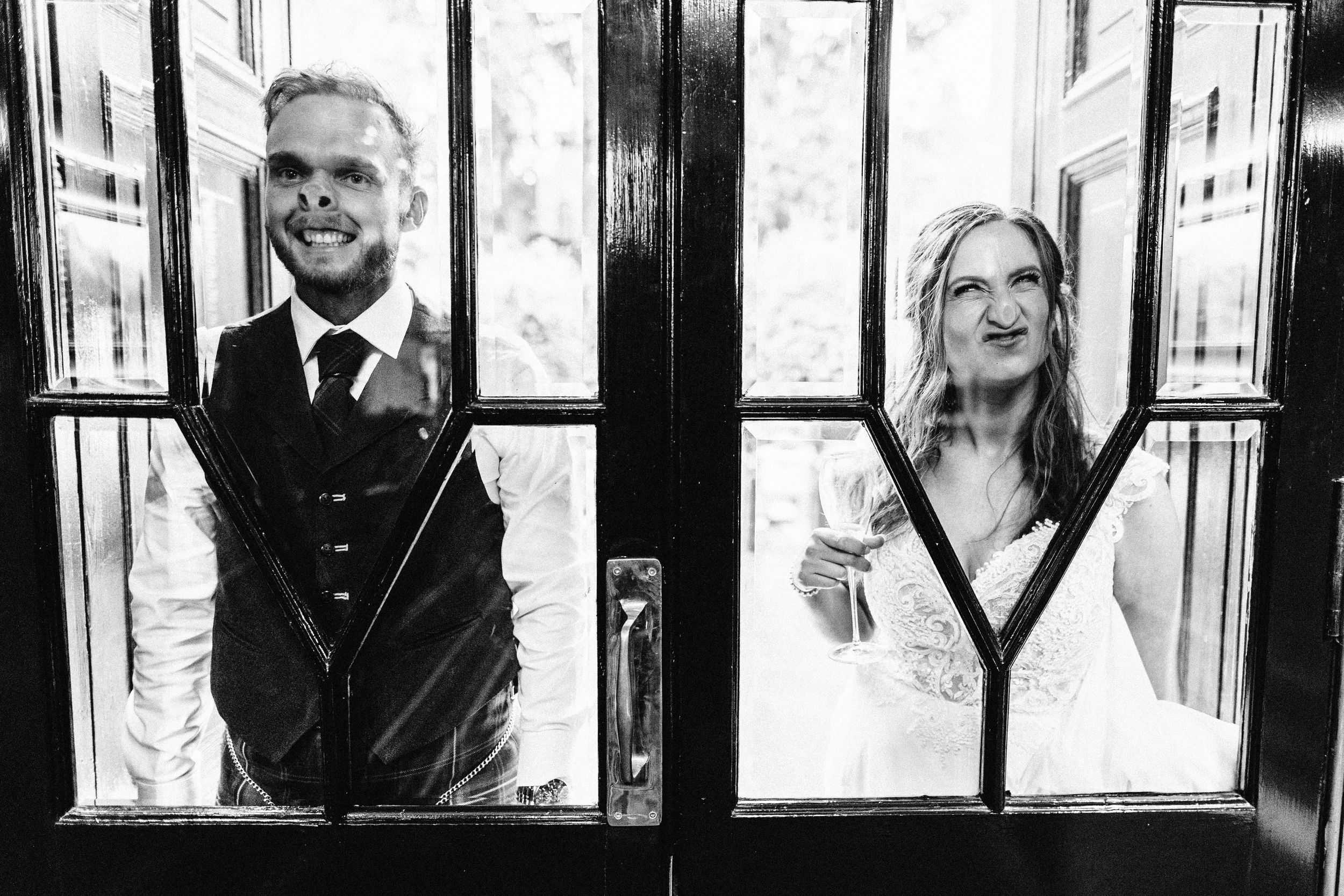 Artistic black and white wedding portraits framed through window panes.