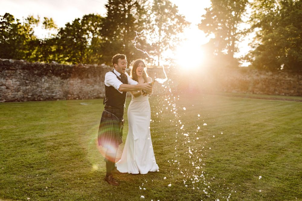 bride and groom spray champagne at golden hour