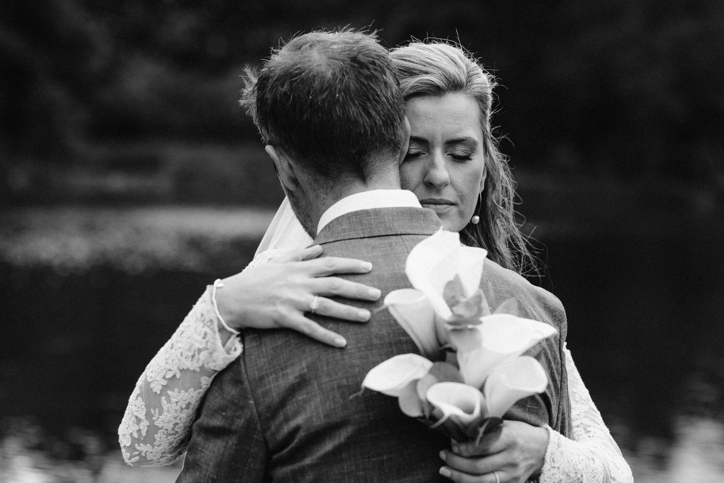 A romantic wedding couple embraces in an intimate black and white moment during their celebration.