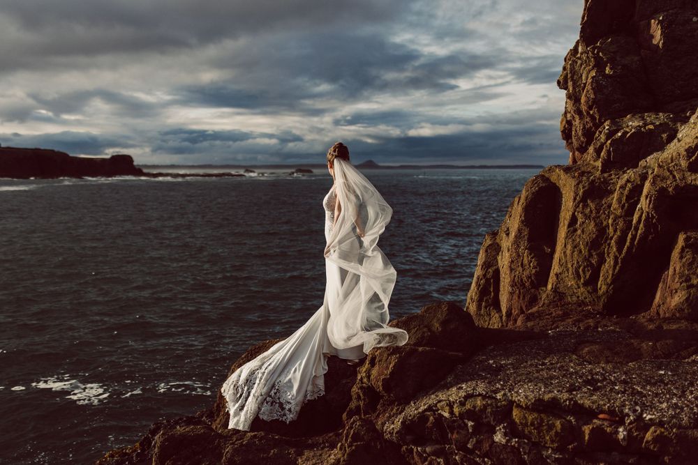 Bride looking out to sea with gorgeous golden light