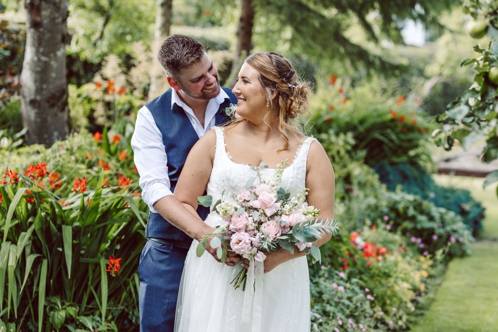 bride and groom hugging in a garden with bright flowers