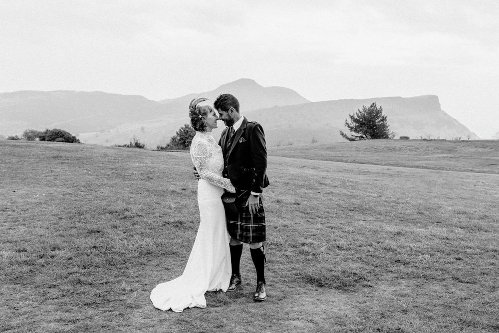 Couple shares intimate moment in scenic mountain meadow landscape.
