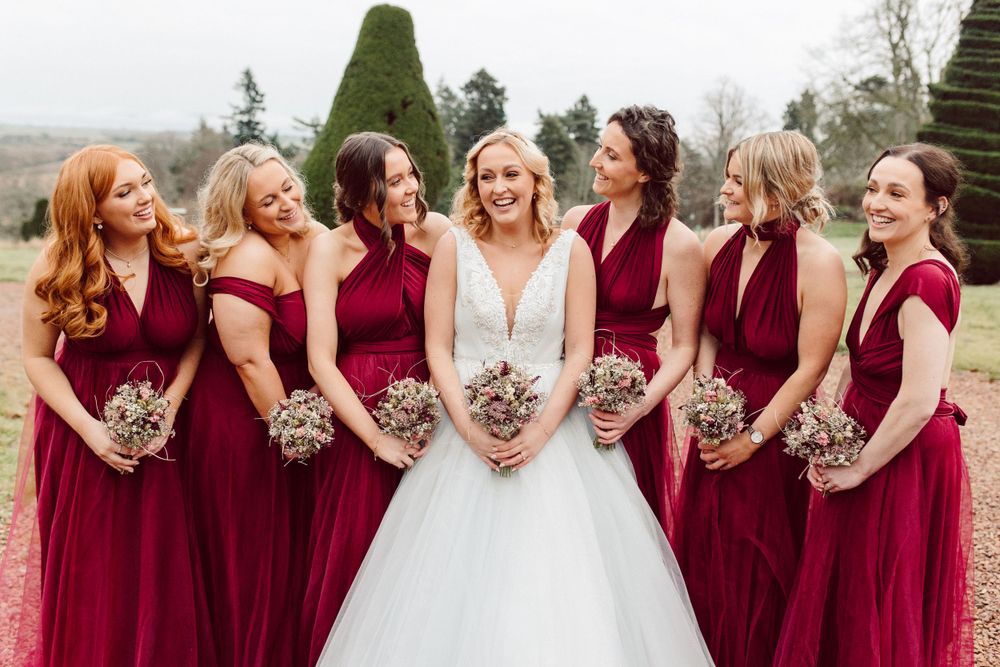 Bride and her bridesmaids laugh together whilst holding their bouquets