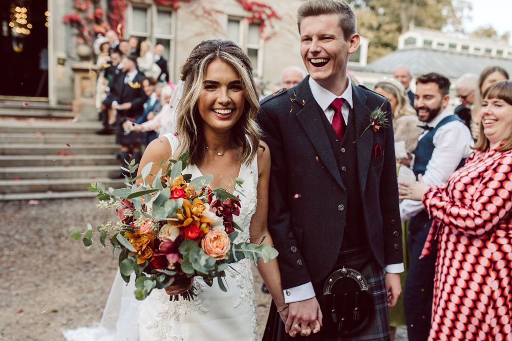 Bride and groom laughing and smiling whilst surrounded by family
