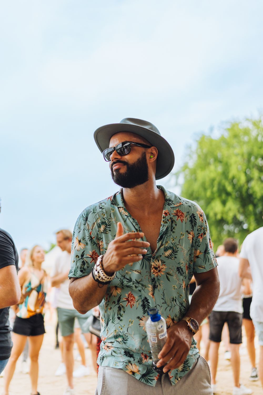 Festival attendee in floral shirt and hat enjoying summer outdoor event.