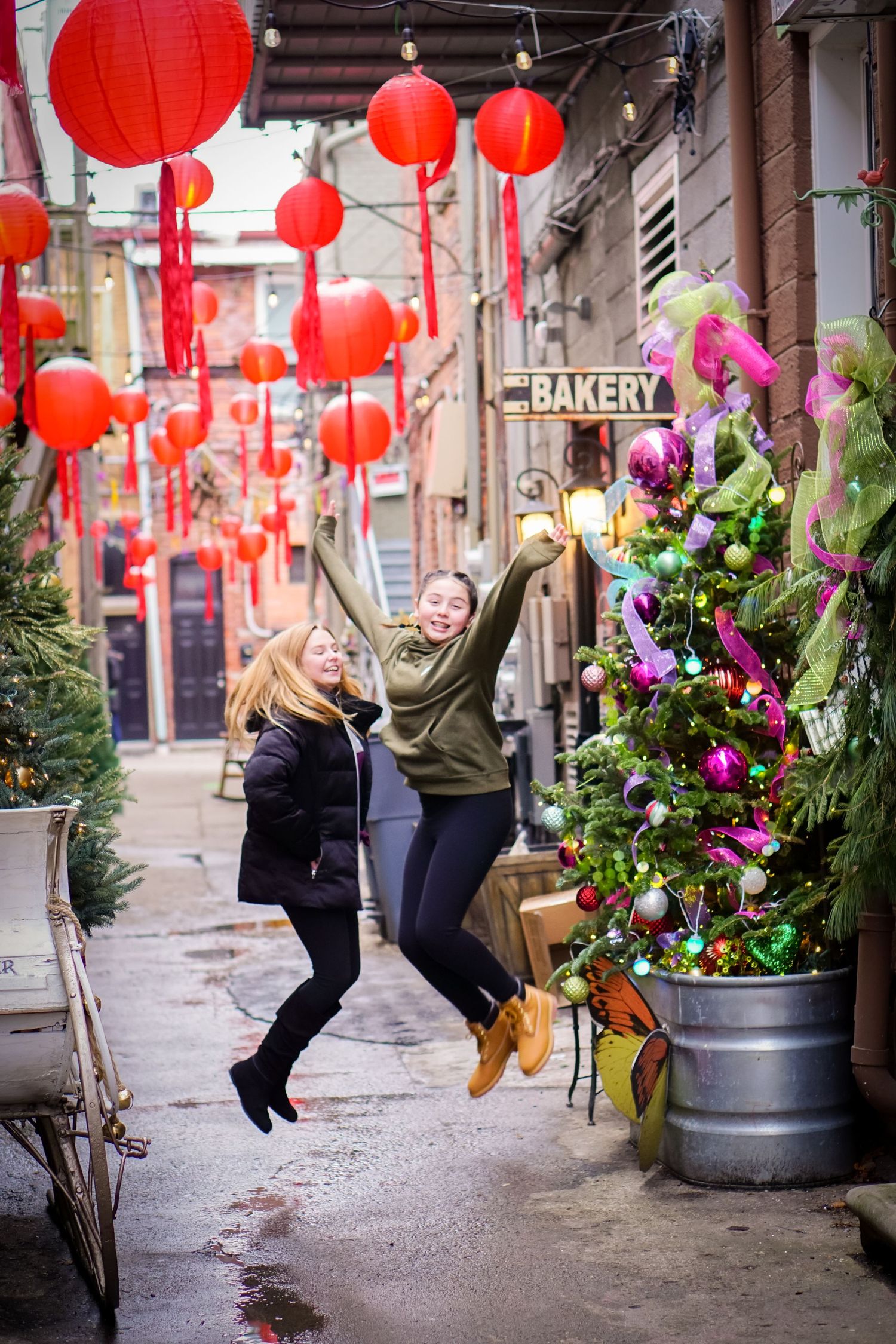 Festive street decorated with red Chinese lanterns and Christmas trees near a bakery.