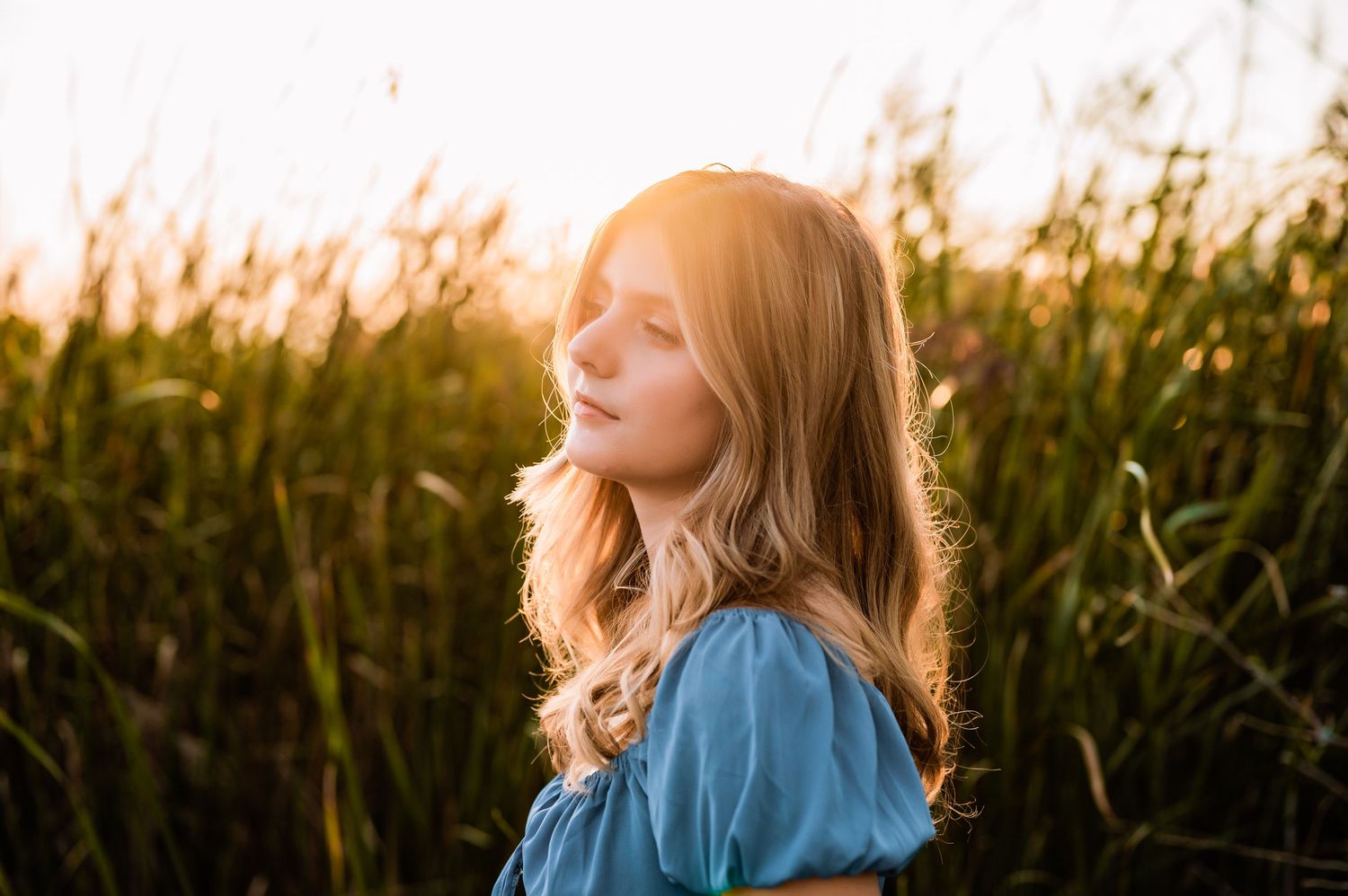 Young girl wearing a blue gown looking off in to the sun in a field on Staten Island,NY