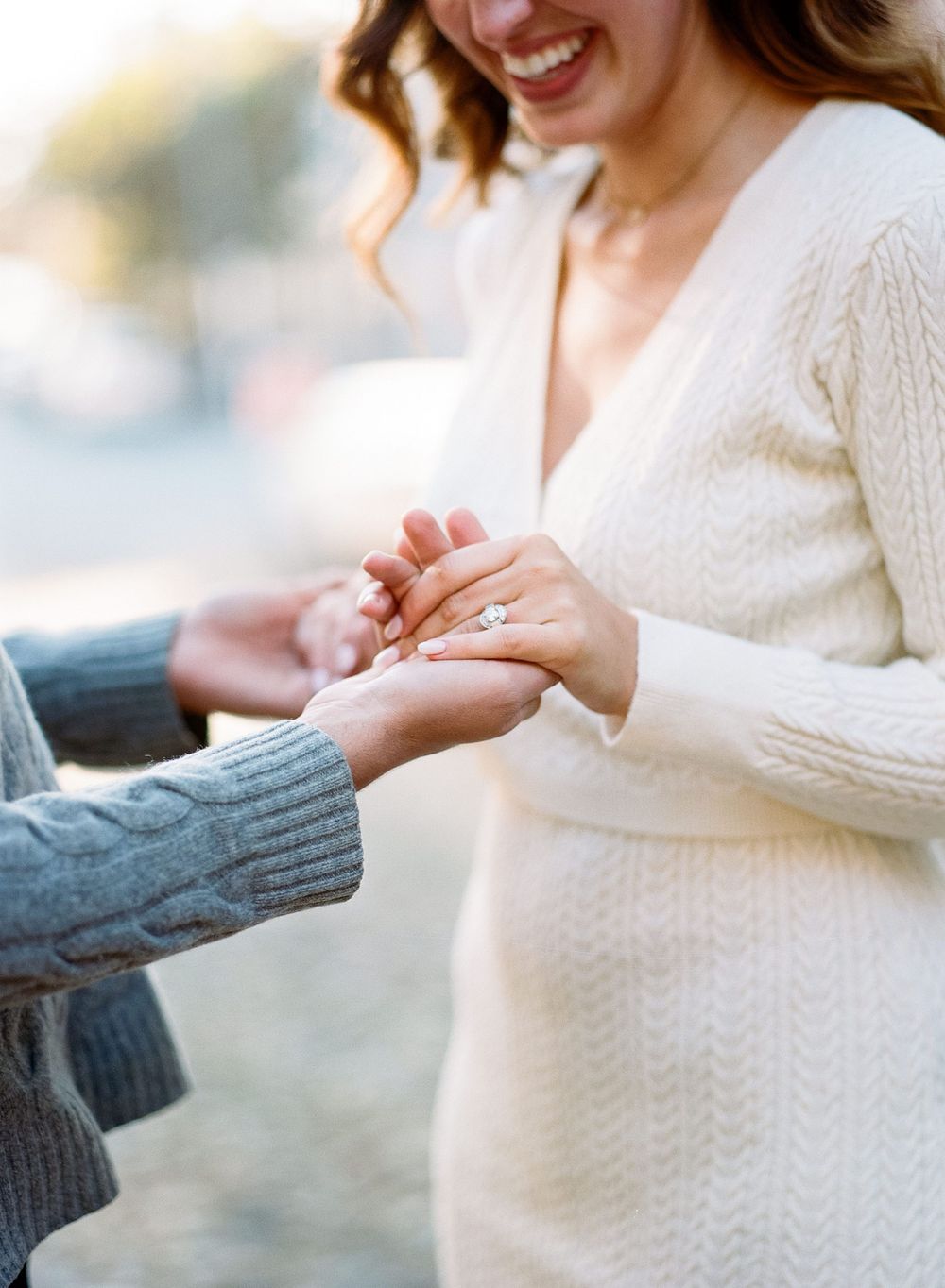Close up of hands exchanging a ring during a romantic outdoor proposal moment.