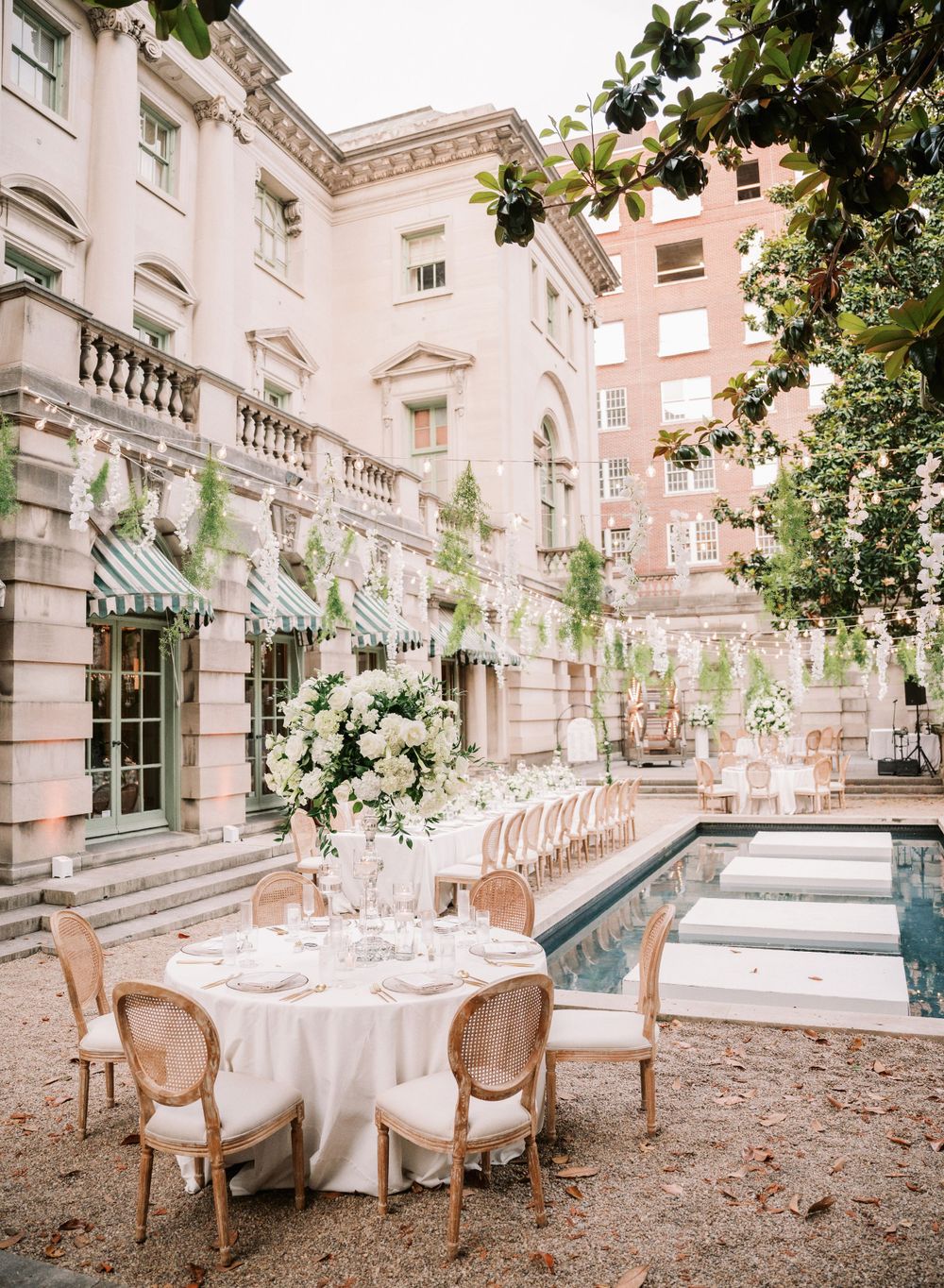 Romantic outdoor wedding reception setup with elegant table settings beside a pool.