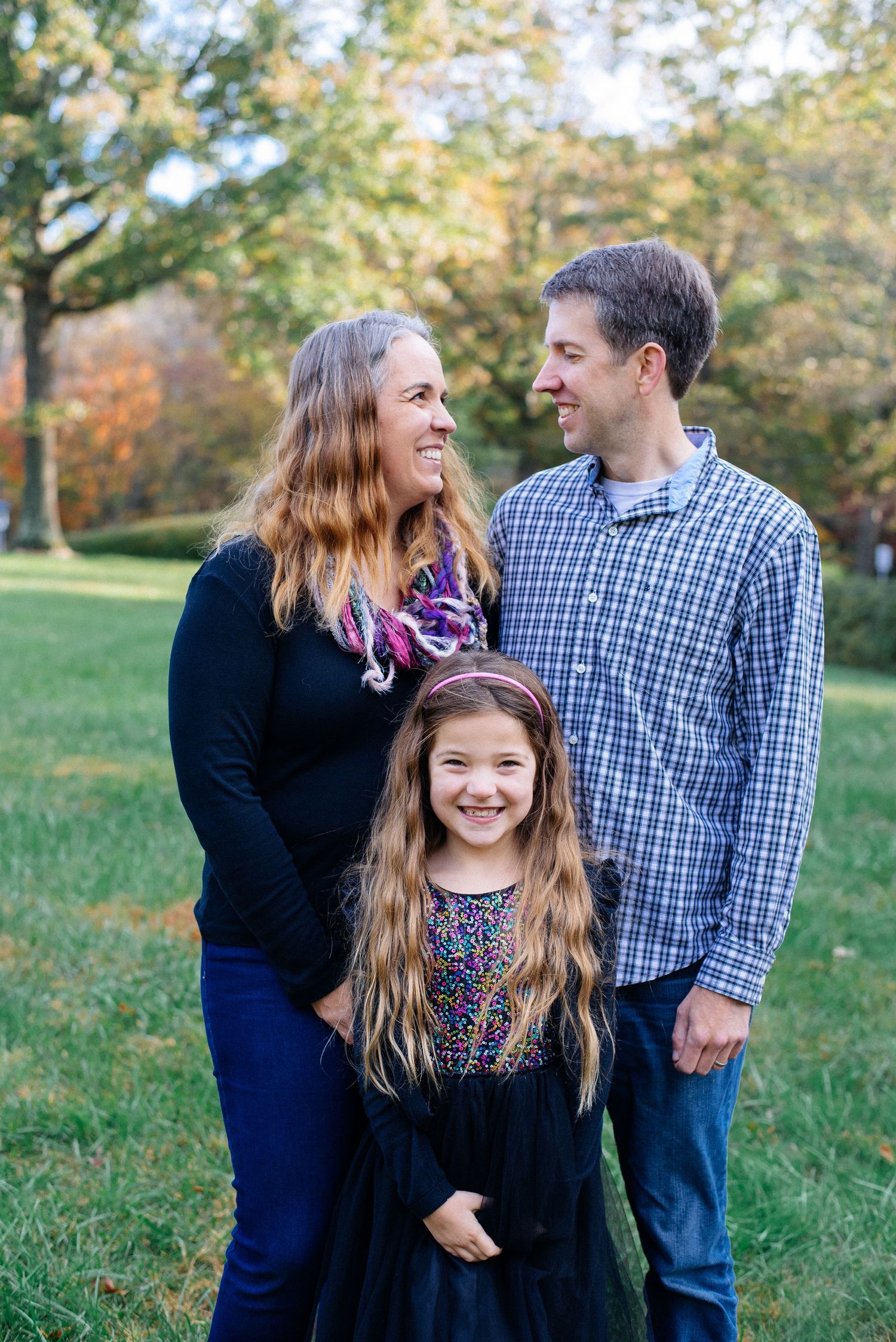 Fall outdoor family portrait with autumn trees in background.
