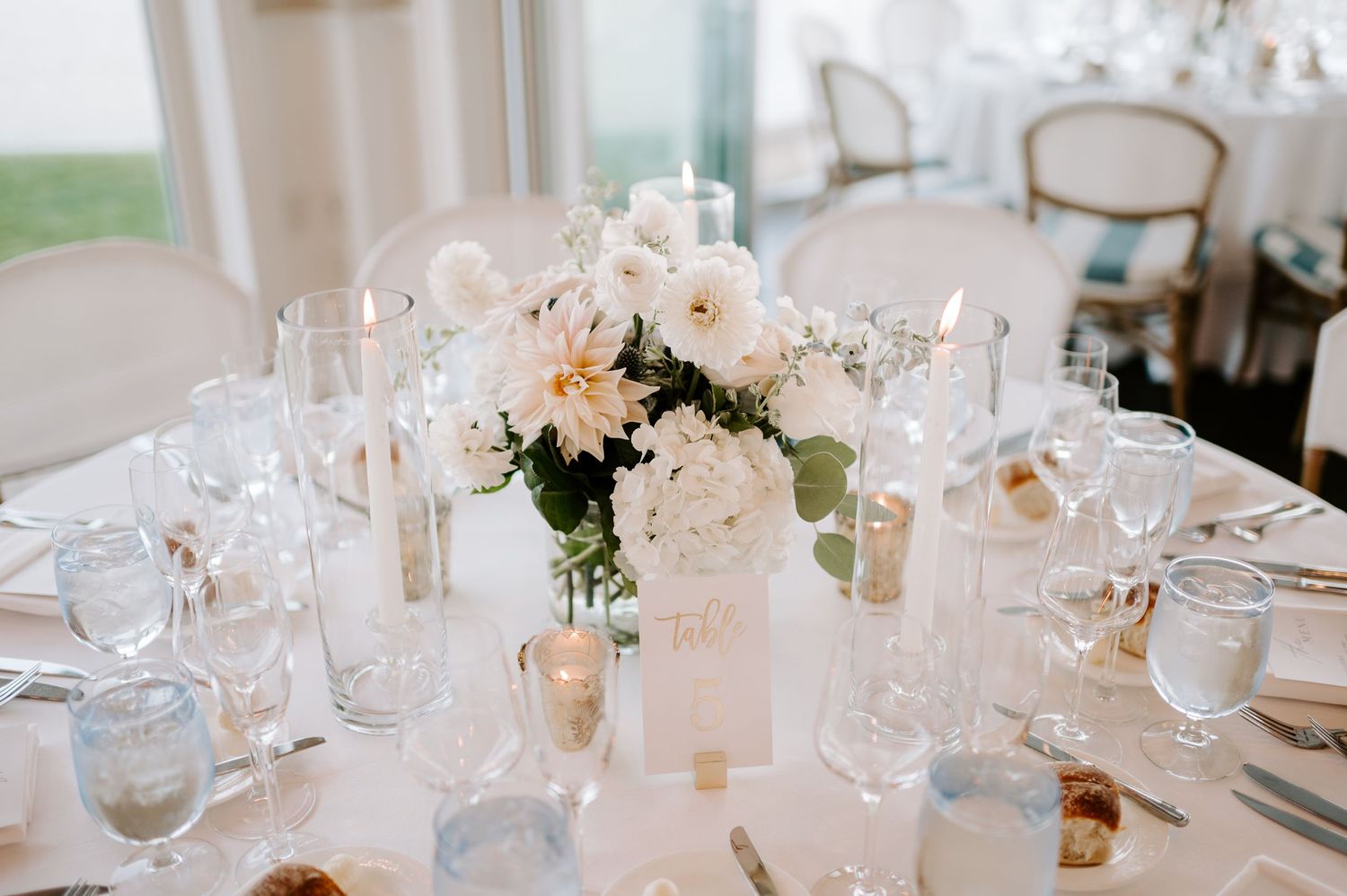 Elegant wedding reception table settings with crystal glassware and white linens.