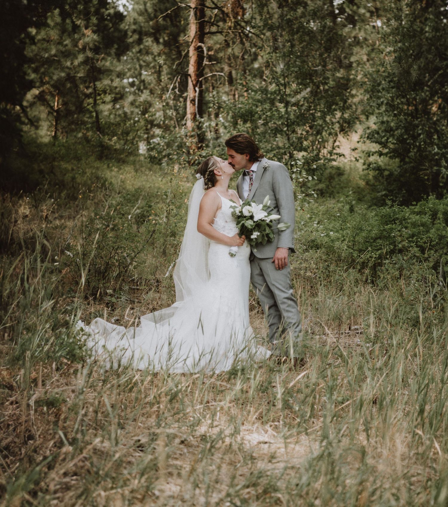 Romantic wedding portrait in forest setting with white dress and grey suit.