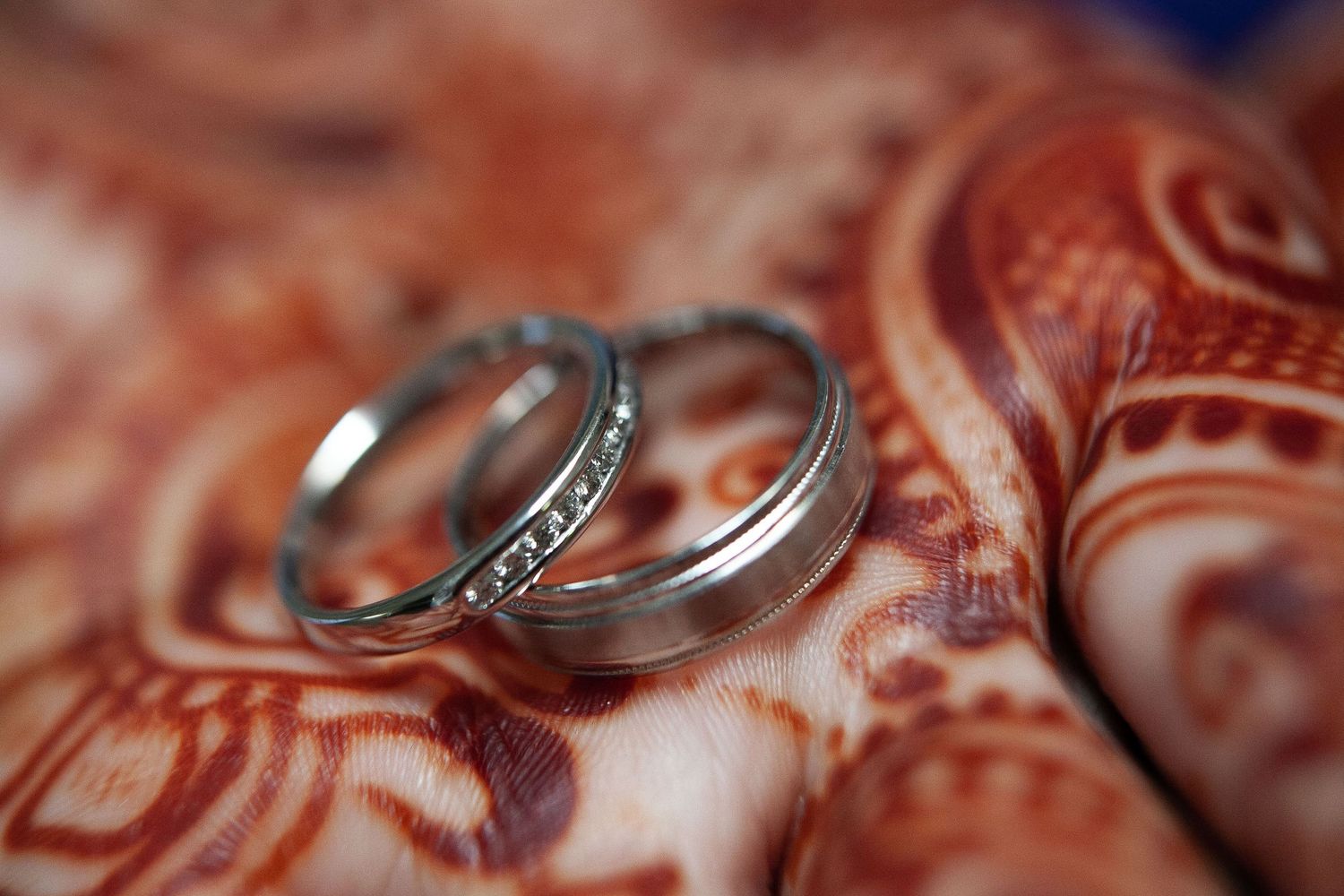 Close-up macro shot of two wedding rings with intricate details resting on a textured surface.