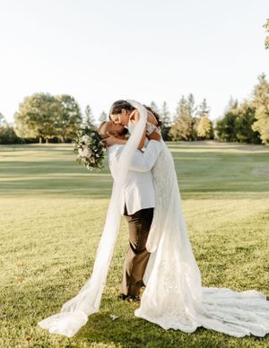 Romantic sunset wedding portrait of couple embracing on a lush green lawn.