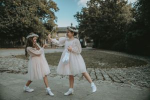 Children in white dresses playing outdoors during a wedding celebration.