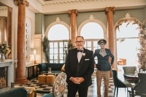 Wedding ceremony in a grand venue with ornate columns and checkered floor.