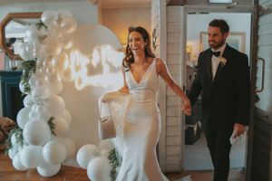 Wedding reception venue decorated with elegant white balloon arrangements and warm lighting.