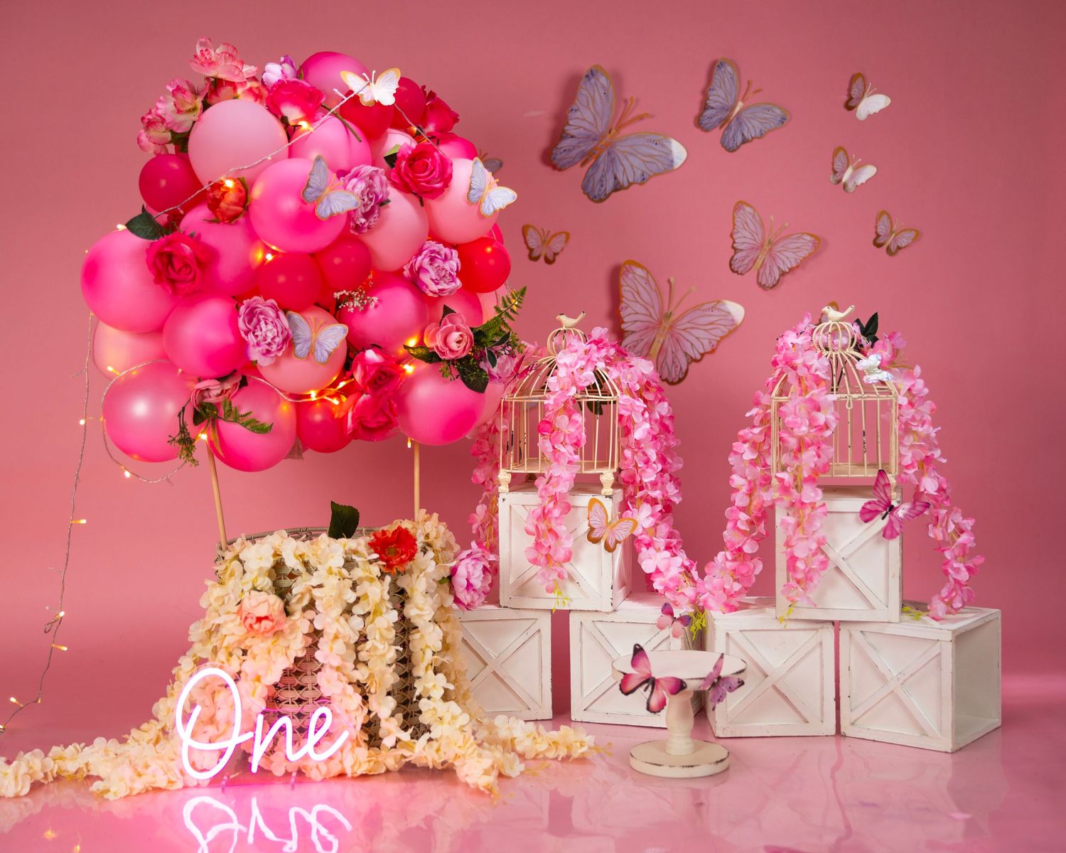 Pink balloon arrangement with butterflies and decorated display boxes for a romantic celebration setup.