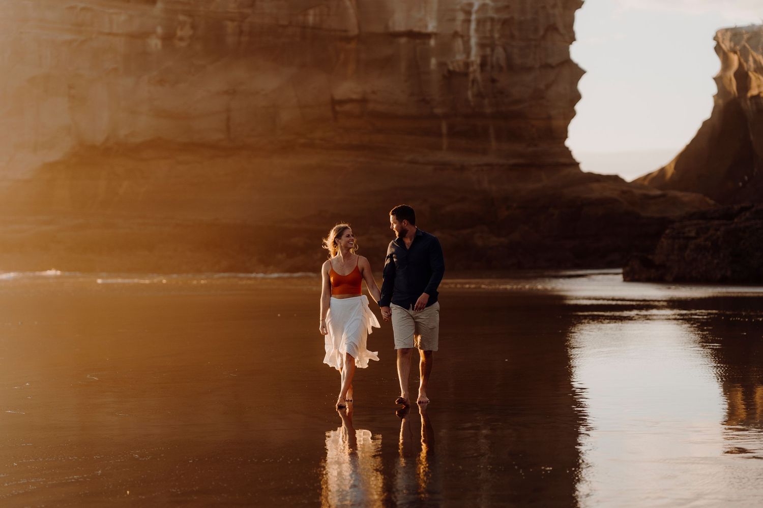 Couple running down beach laughing