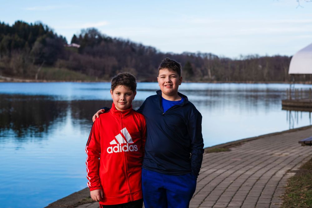 Two people in athletic wear standing on dock by serene lake.