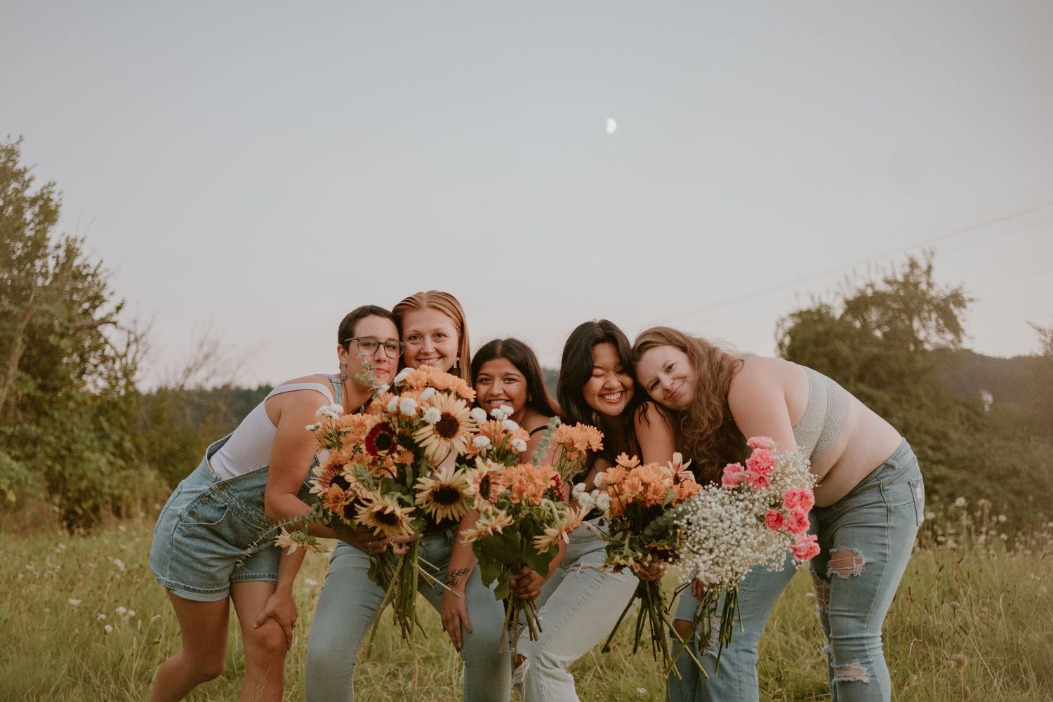 Candid outdoor family portrait session in a meadow with natural lighting and floral arrangements.