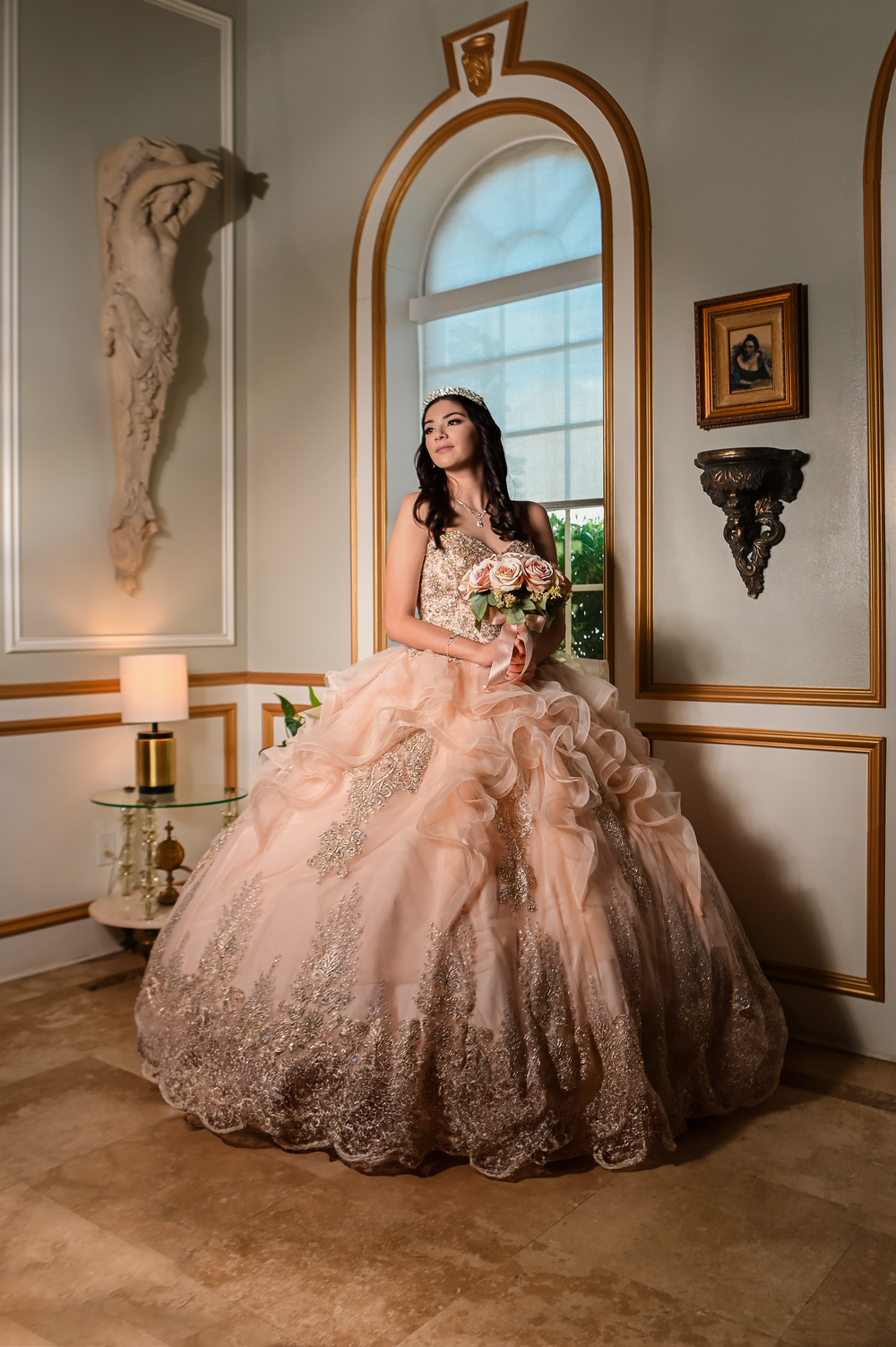 Luxurious peach-colored ballgown featured in an elegant room with arched windows and classical decor.