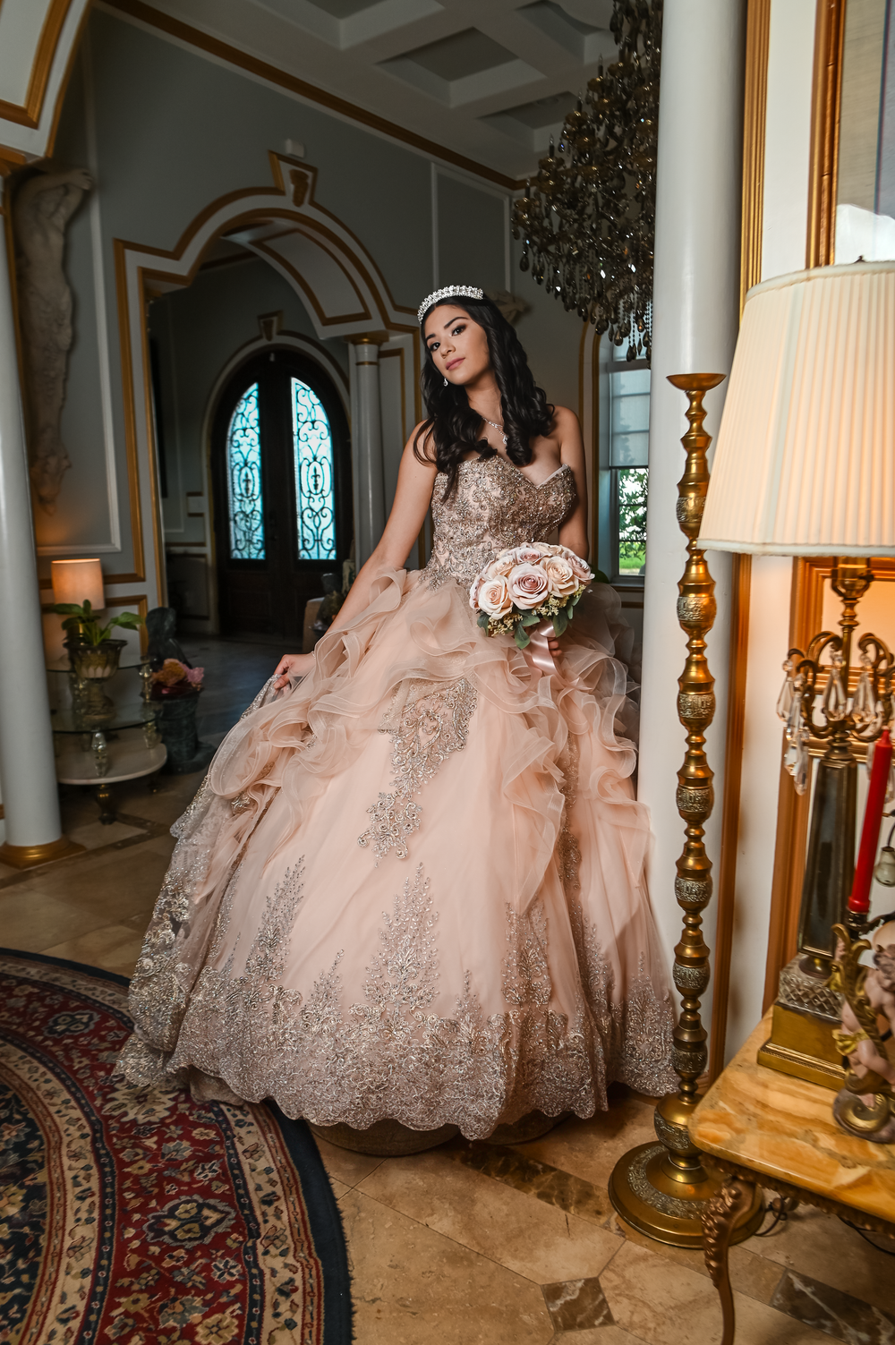 Blush pink princess ballgown photographed in elegant foyer with ornate decor and lighting.