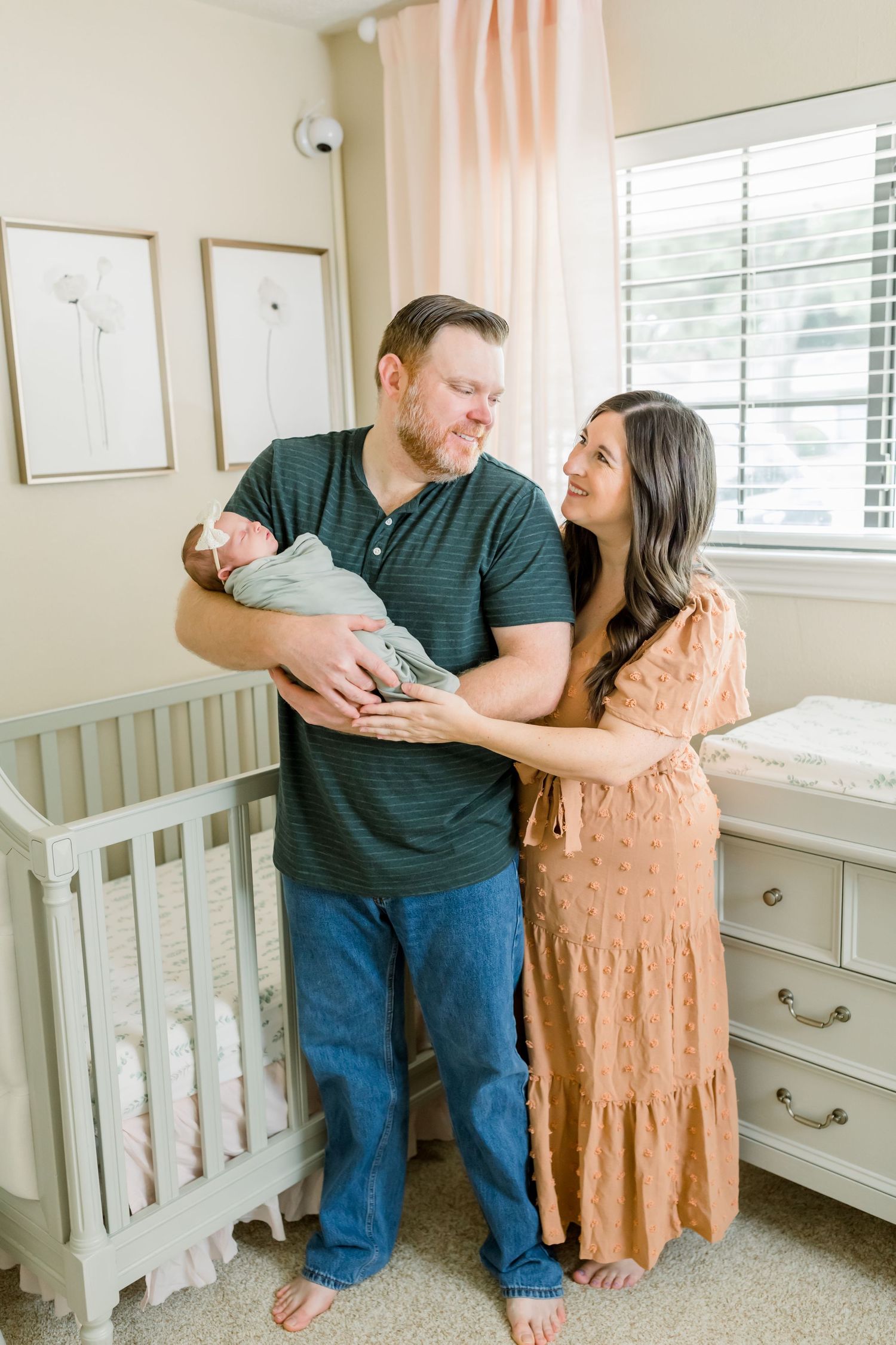 A couple shares an intimate moment with their newborn baby in a peaceful nursery setting.