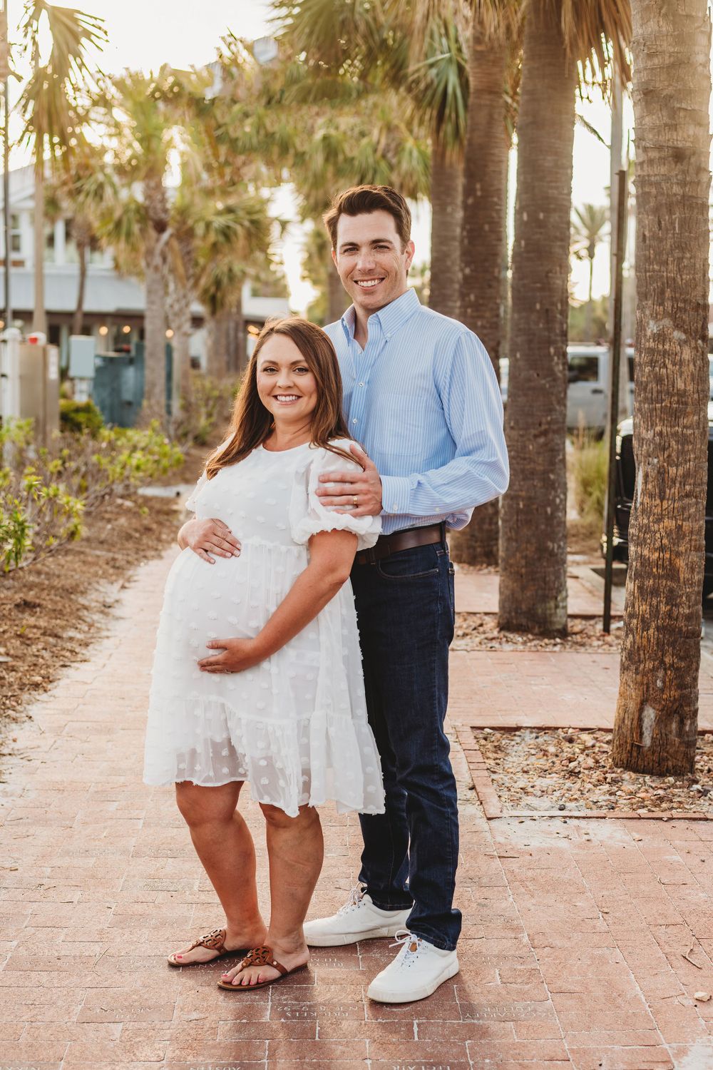 Family enjoying a sunset walk along a brick pathway lined with palm trees.