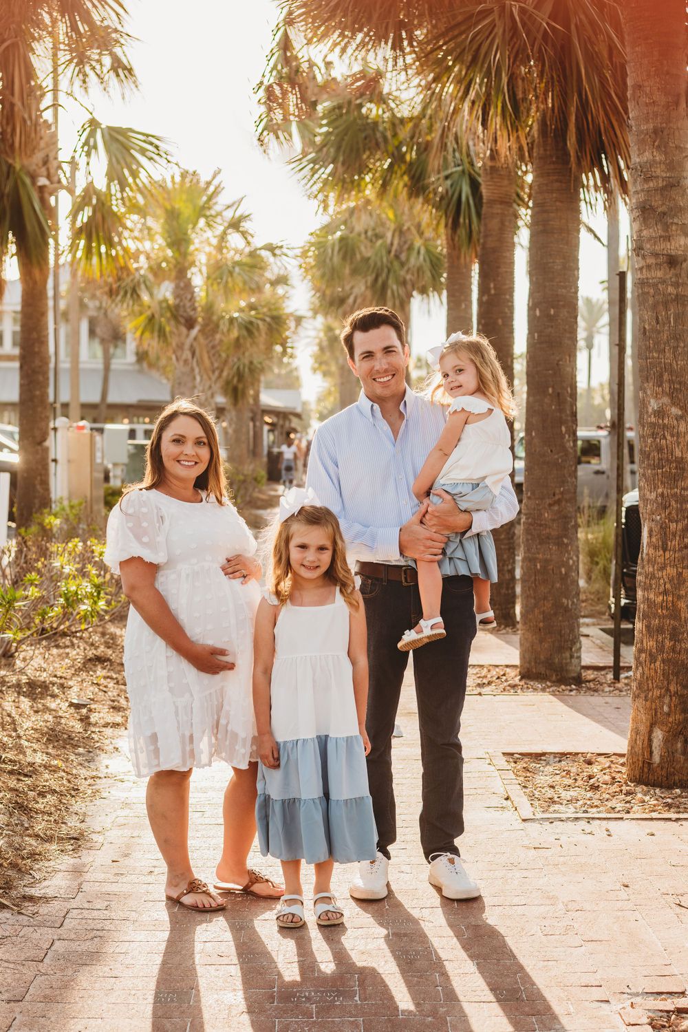 Family portrait on a palm tree-lined path during golden hour.