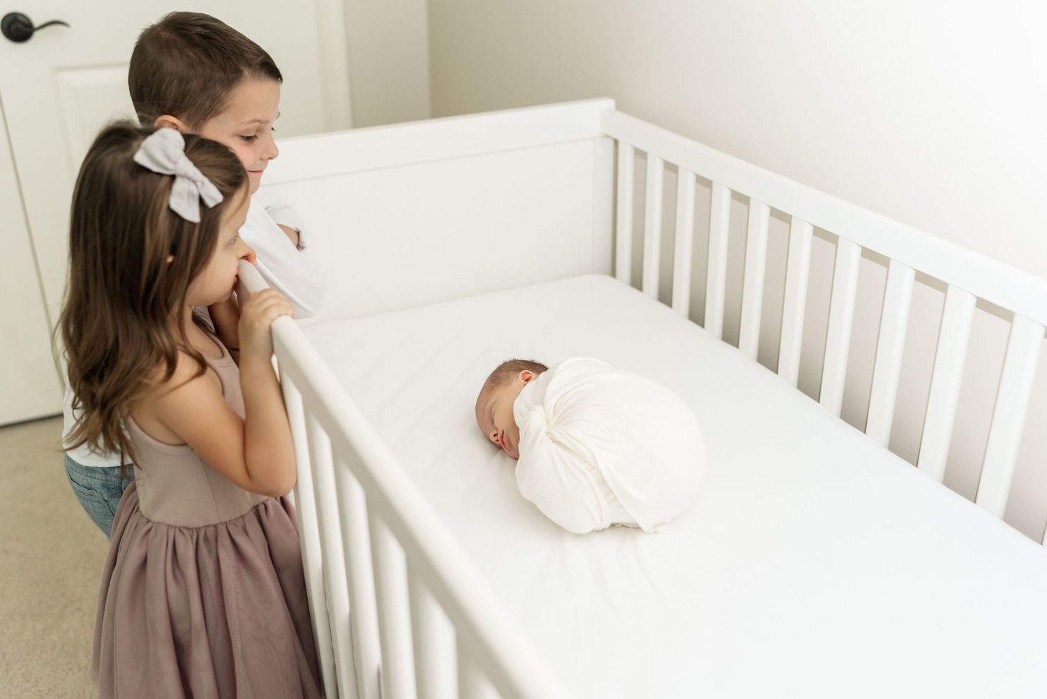 siblings looking at baby