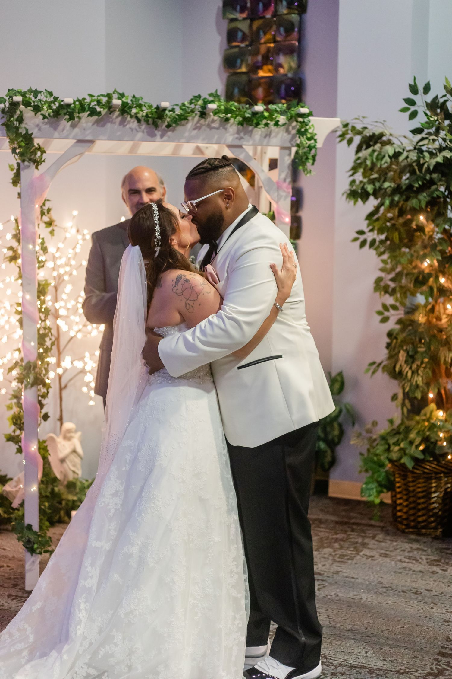 Newlyweds share their first dance in an intimate indoor venue with string lights and greenery.