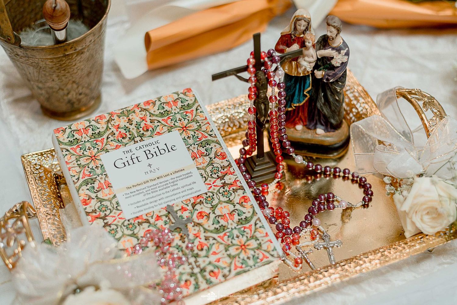 Vintage-style wedding decor with floral book, ornate figurines, and decorative items on metallic tray.