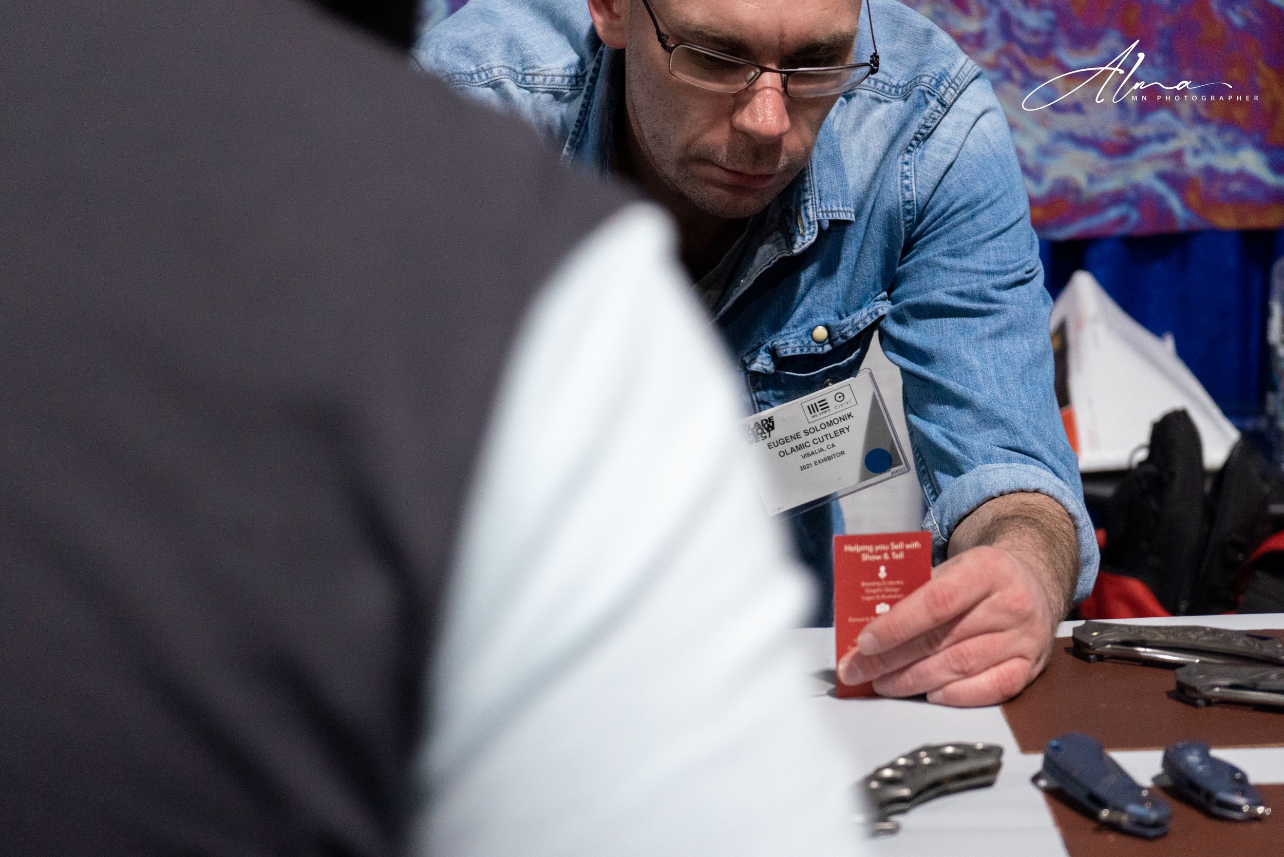 Close-up shot of hands holding a red can at a table with various items.