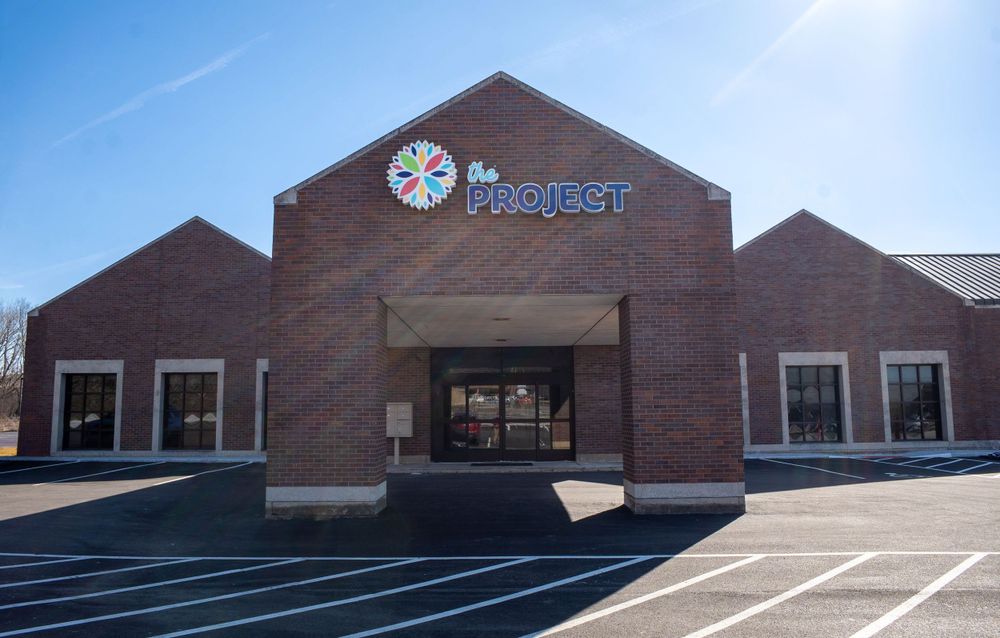 Modern brick building exterior with Project signage and clock mounted above the entrance. Quad Cities Real Estate Photography