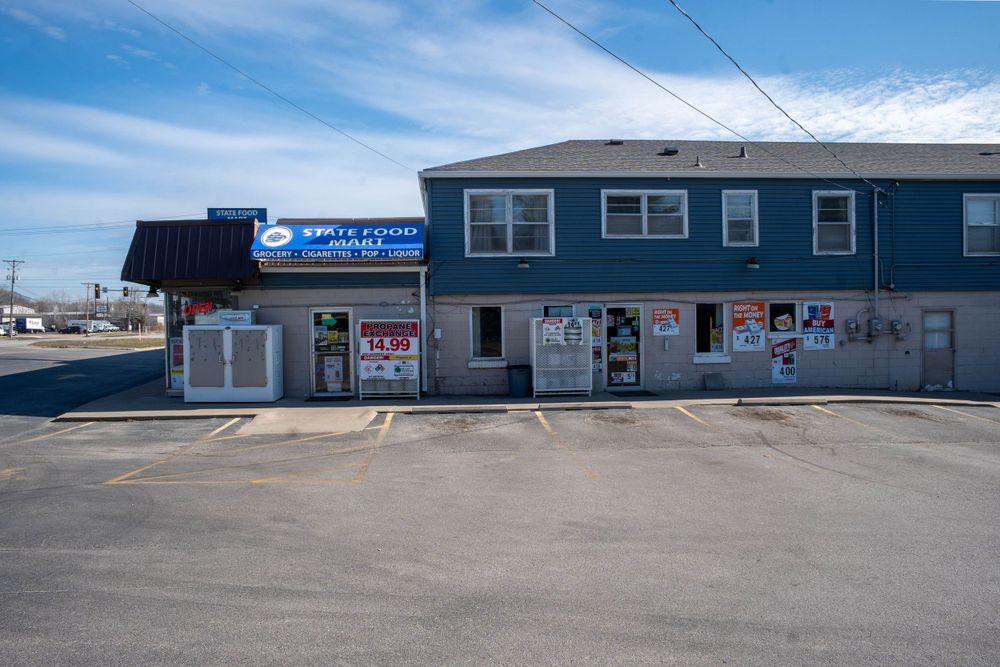 Two-story commercial building with blue awning and storefront signs in a parking lot. Quad Cities Real Estate Photography