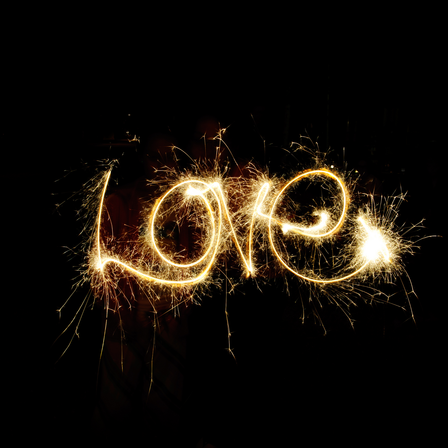 Light painting photography creating glowing trails against black background.