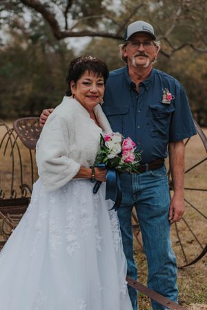 Couple in wedding attire sharing a tender moment outdoors in casual country style.